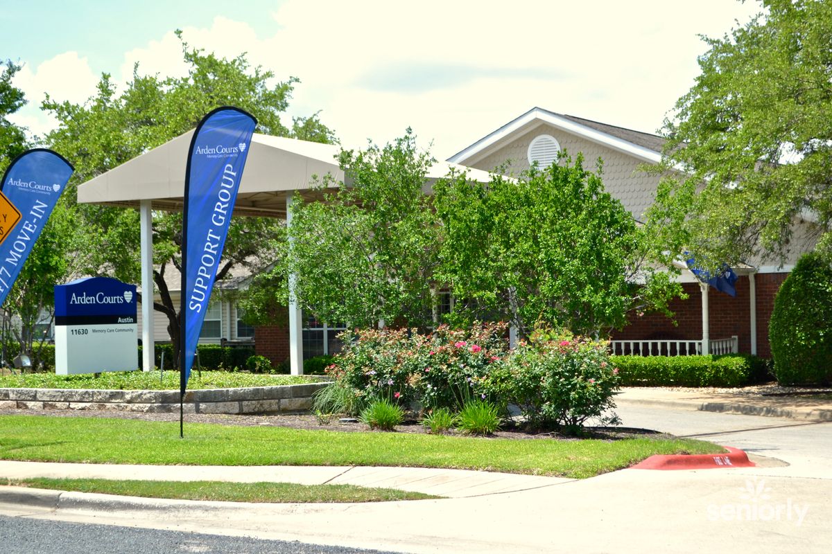 A residential building with surrounding greenery and a small driveway.