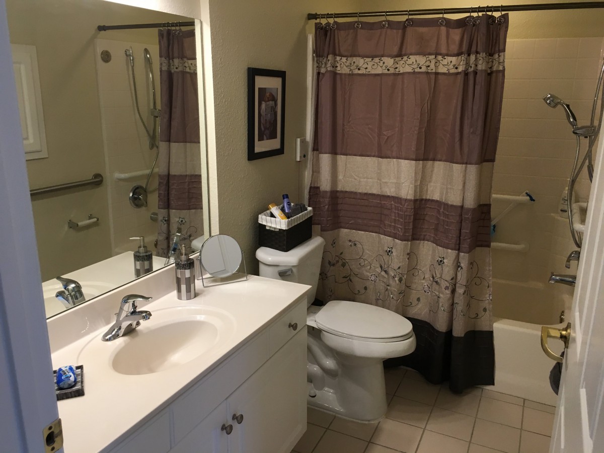 A neatly organized bathroom with a shower curtain, sink, and toilet.