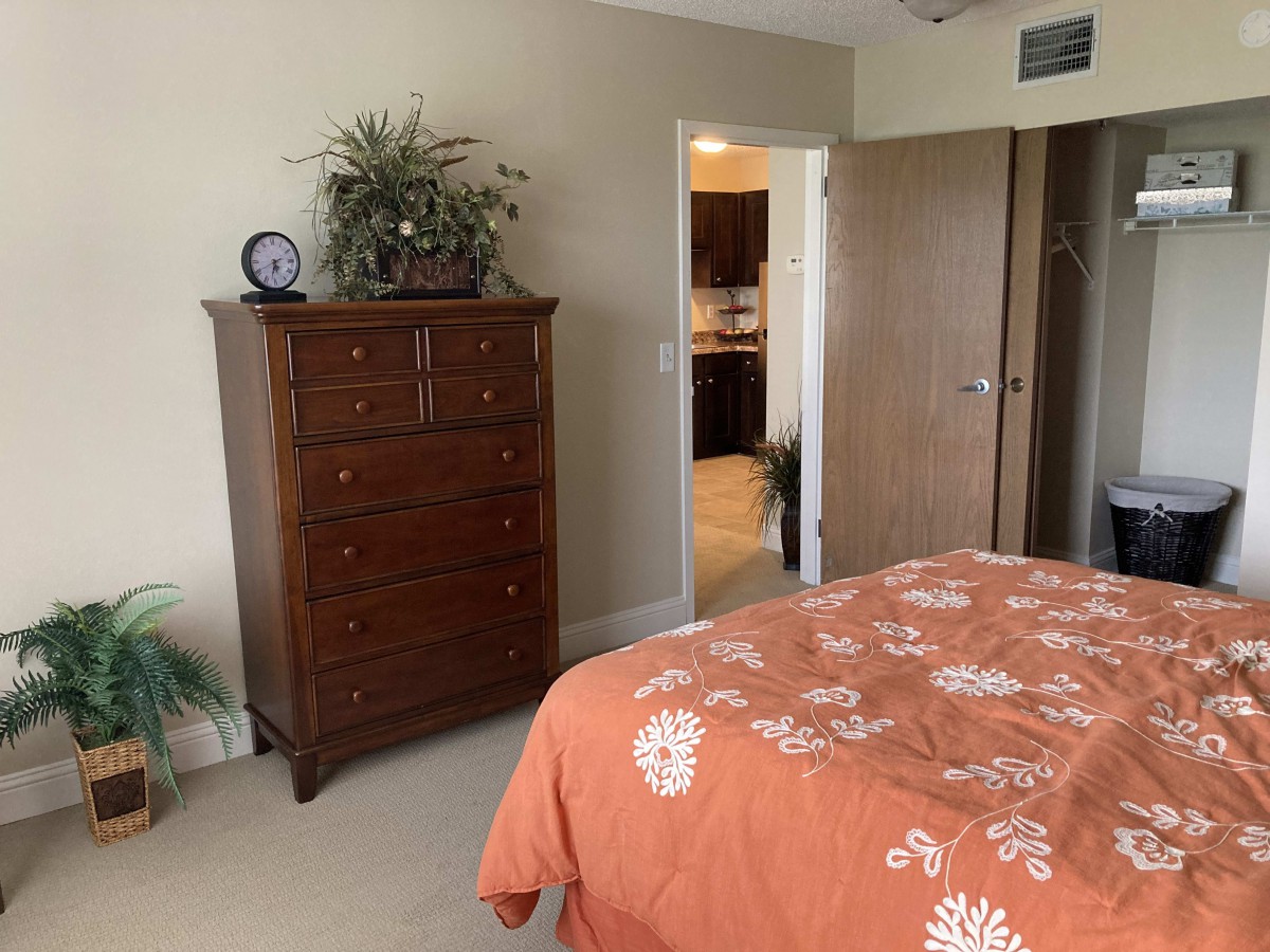 A cozy bedroom with a wooden dresser and an orange floral bedspread.