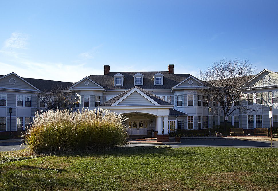 A large estate with colonial-style architecture surrounded by a well-maintained lawn.