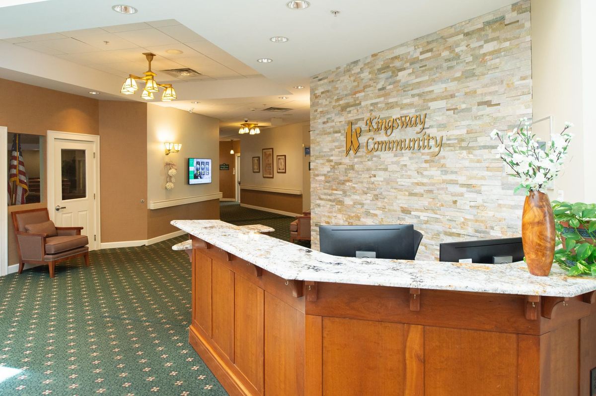 A welcoming hotel reception area with a wooden desk and decorative wall.
