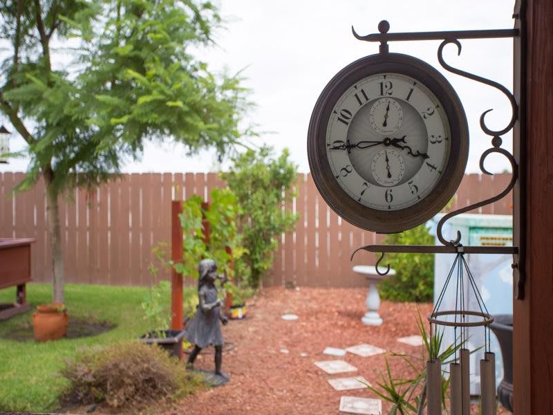 A garden with a large decorative clock and a stone pathway.