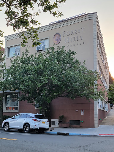 A view of a building with a tree and parked car in front.