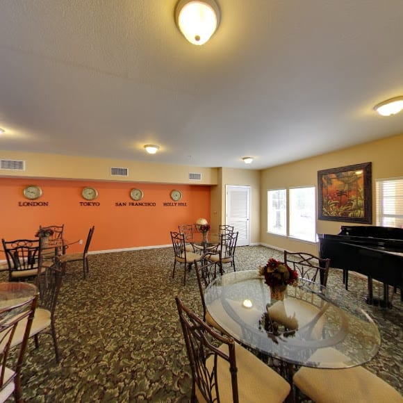 A cozy living room with dining tables, a piano, and decorative elements.