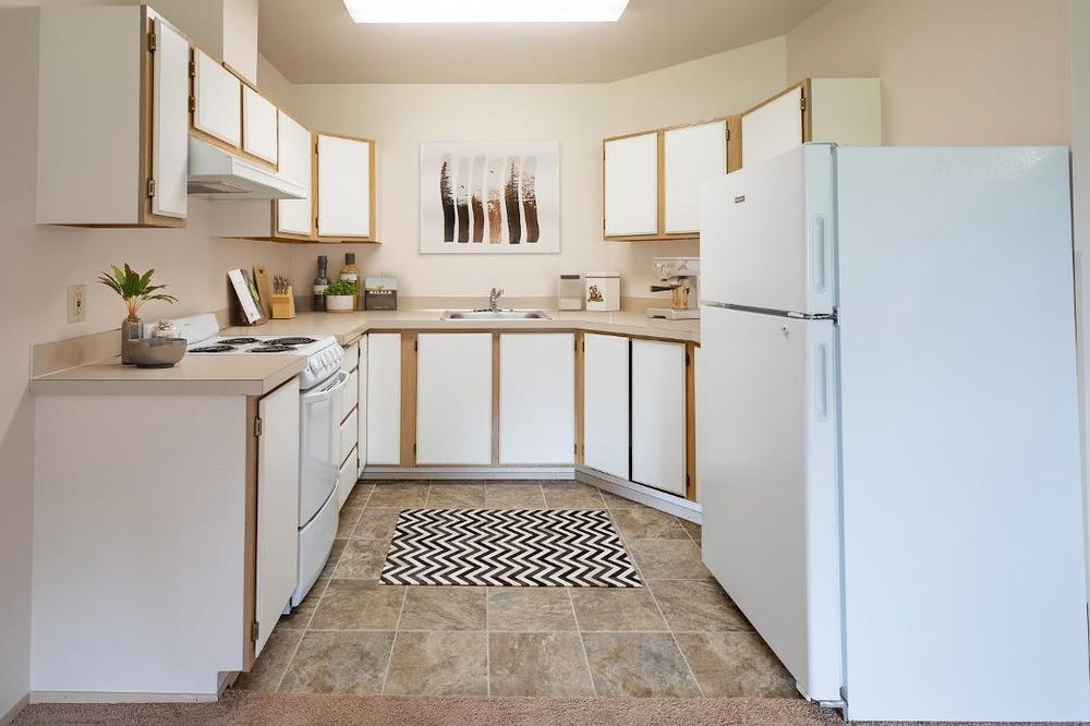 A clean and organized kitchen with white cabinets and appliances.