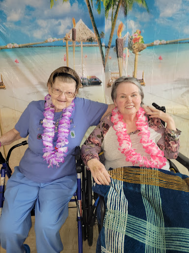 Two friends enjoying a tropical-themed celebration, both adorned with colorful leis.