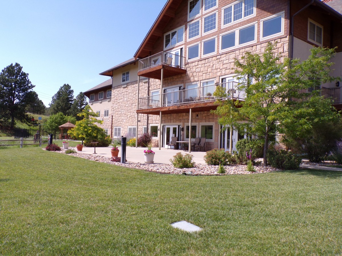 A spacious house with large windows and balconies overlooking a well-maintained lawn.