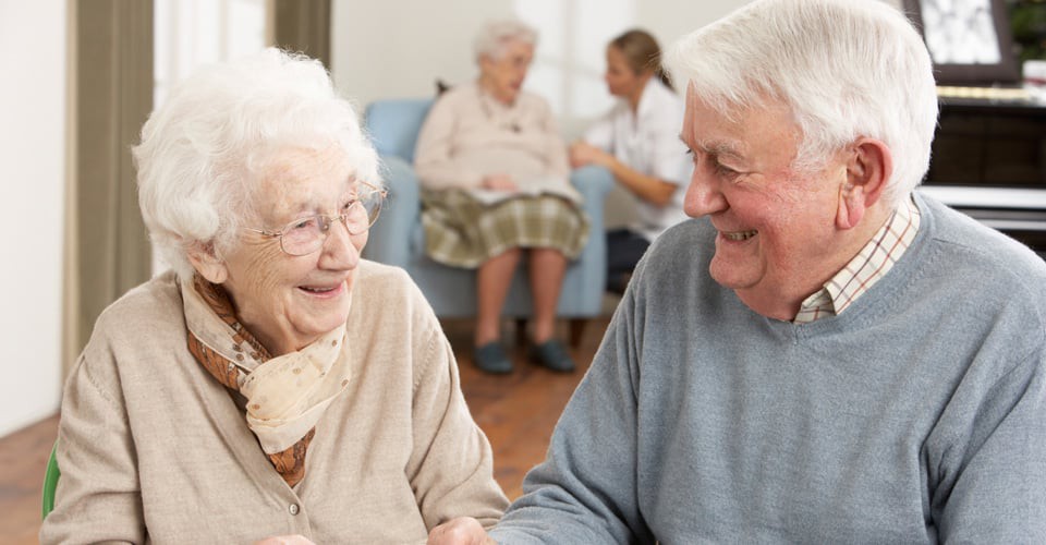 Elderly individuals sharing a joyful moment in a nursing home setting.