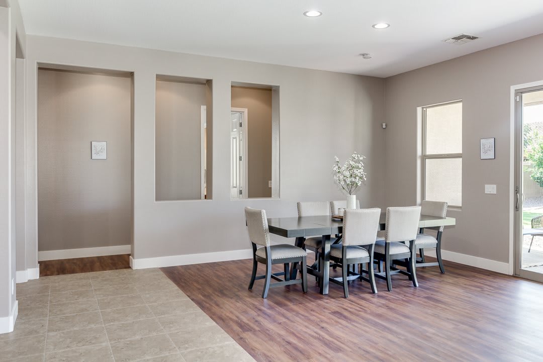 A modern dining room with a sleek table and chairs, featuring wood flooring and neutral tones in an open space.