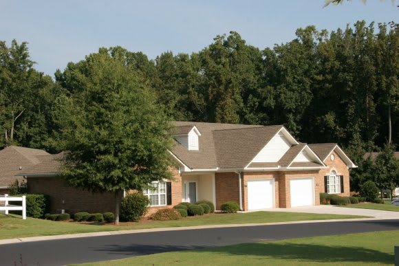 A suburban house with a driveway and surrounding greenery.