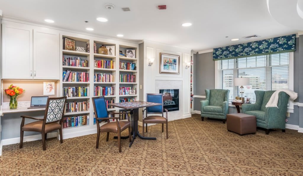 A cozy reading area with a large bookshelf, comfortable seating, and a fireplace.