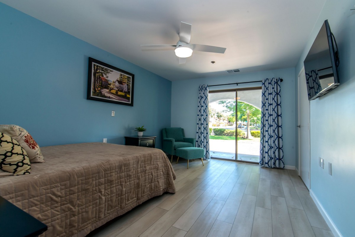 A spacious bedroom with a bed, comfortable chair, and sliding glass doors leading outside.