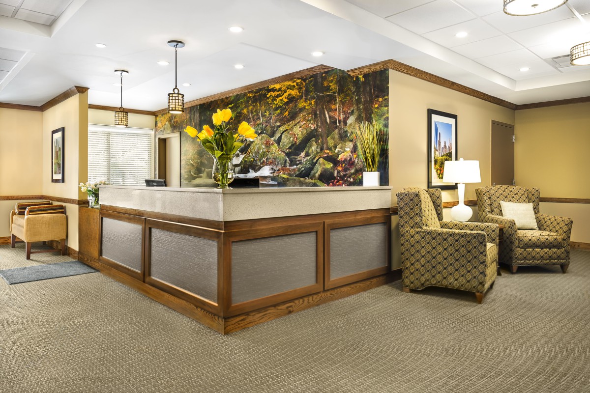 A well-decorated lobby area featuring a reception desk, comfortable seating, and vibrant floral arrangements.