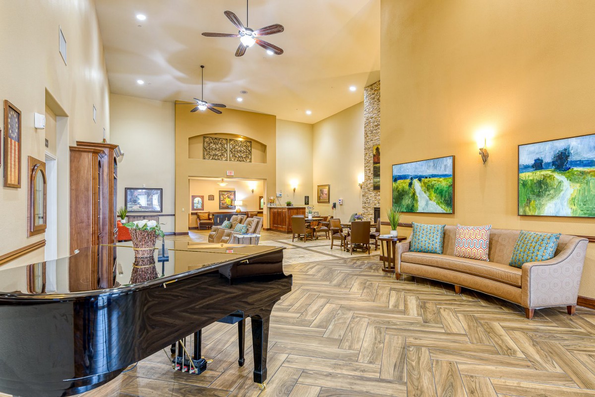 A spacious and elegantly decorated lobby area featuring a grand piano, comfortable seating, and ambient lighting.