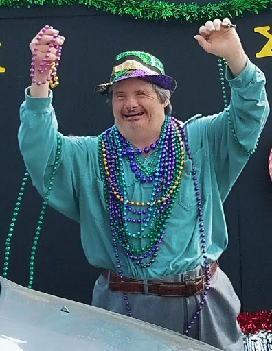 A joyful participant at a Mardi Gras celebration, adorned with colorful beads and celebrating the festive spirit.