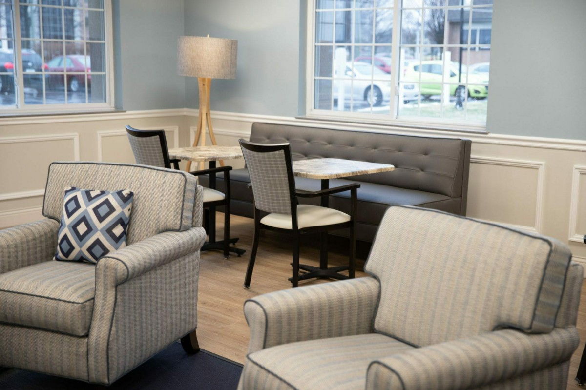 A cozy lounge area with comfortable seating, tables, and a large window.