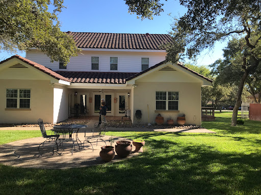 A sunny afternoon view of a spacious home with a well-kept backyard.