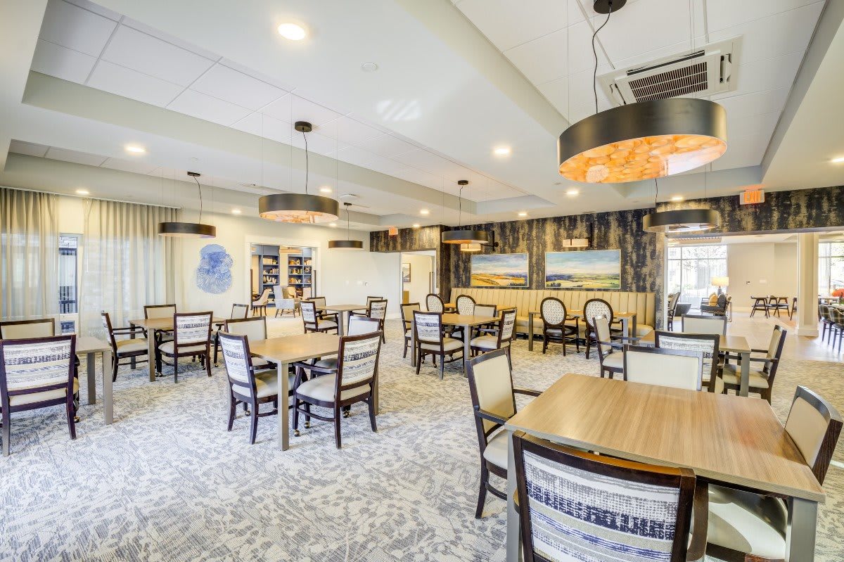A modern dining area with neatly arranged tables and chairs, featuring stylish lighting fixtures and contemporary decor.