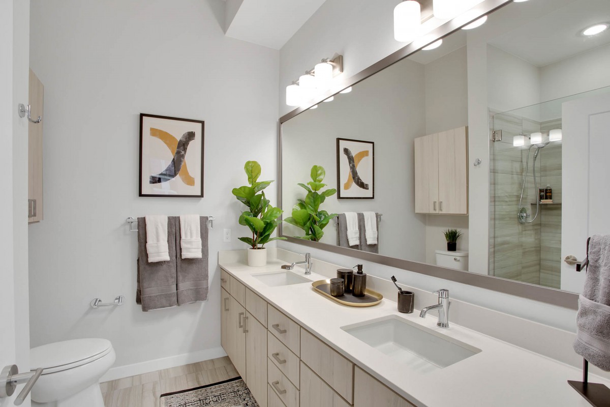 A modern bathroom featuring a large mirror, stylish decor, and indoor plants.
