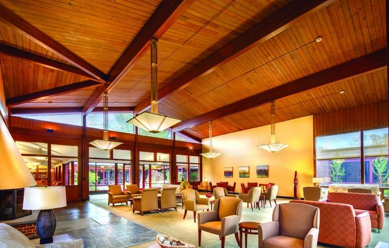 A spacious lobby with a wooden ceiling, modern furniture, and elegant lighting.