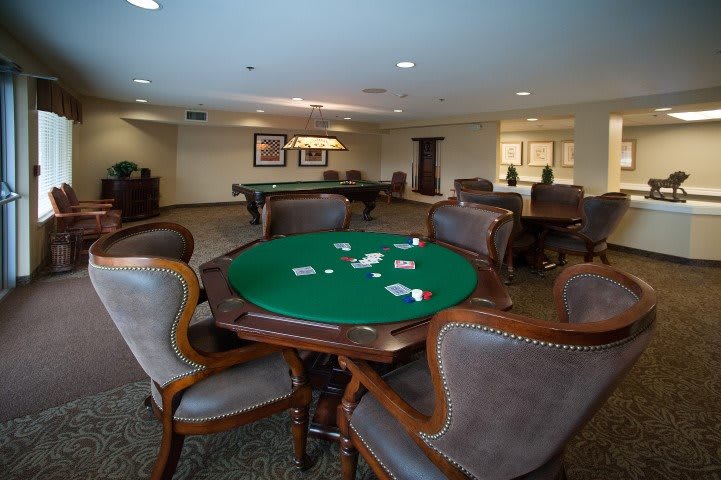 A cozy game room with a poker table, chairs, and playing cards.