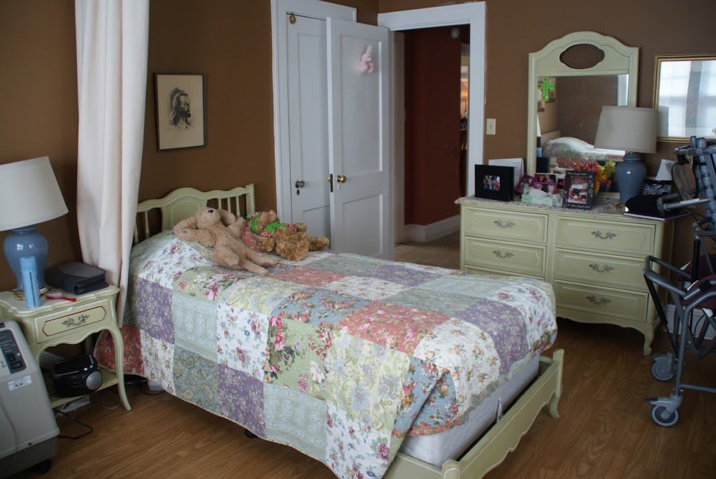 A cozy bedroom with a vintage style, featuring a bed with a patchwork quilt and a dresser with a mirror.