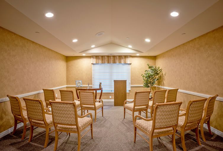 An empty conference room with rows of chairs and a lectern at the front.