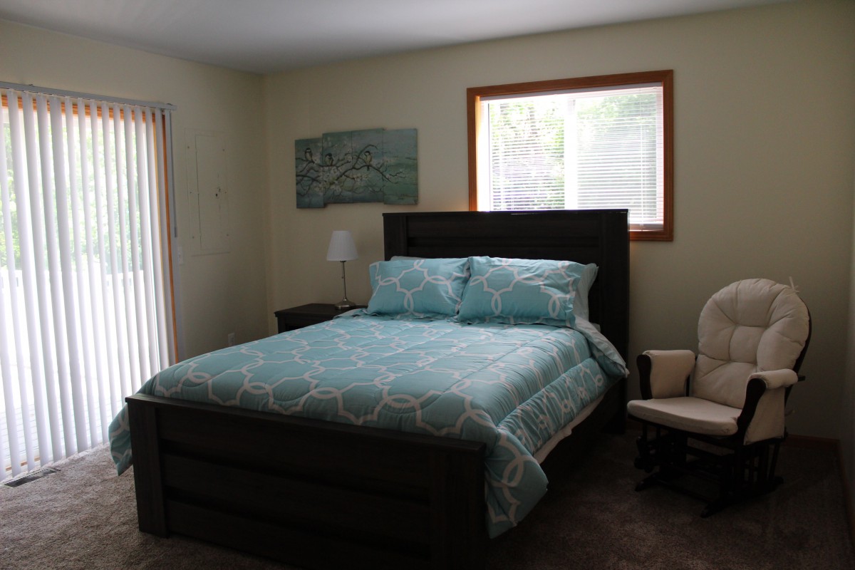 A cozy bedroom with a neatly made bed, a window, and simple decor.