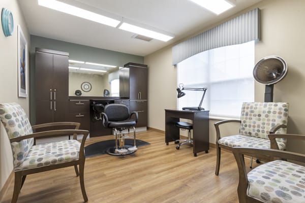 A well-lit salon interior featuring a barber chair, mirror, and seating area.
