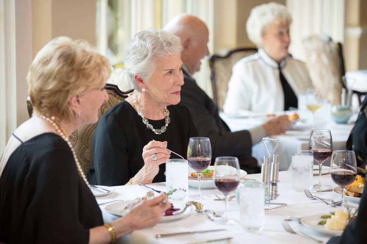 A group of elderly people enjoying a meal together in a formal dining setting.