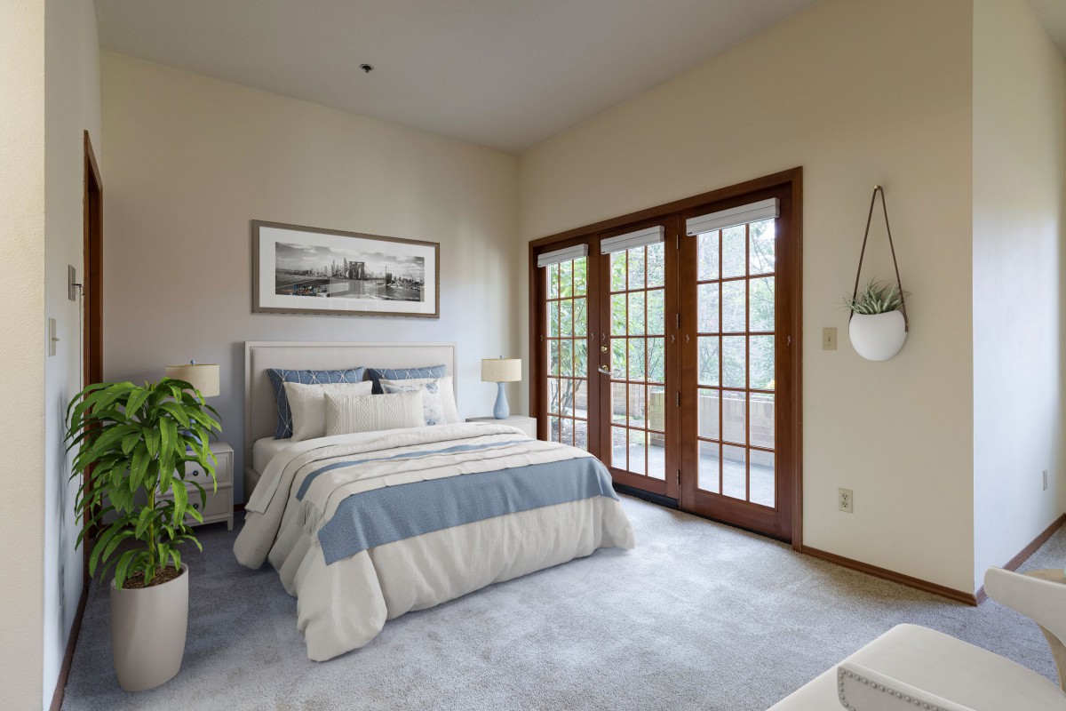 A cozy bedroom with a neatly made bed, featuring French doors and abundant natural light.