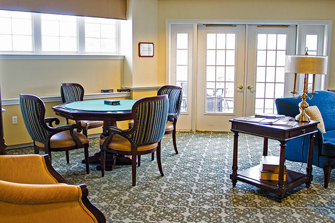 A well-furnished room with a round table, several chairs, and a patterned carpet.
