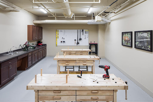 A well-equipped woodworking workshop featuring multiple work tables and tool storage.