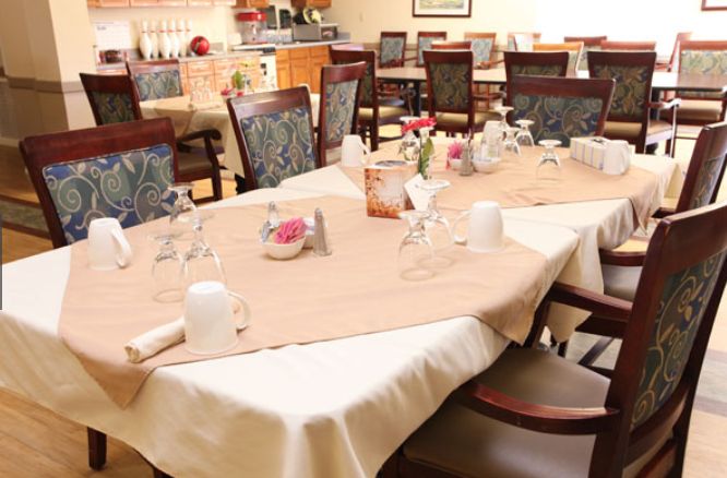 A well-arranged dining area with tables set for guests, featuring elegant tableware and comfortable seating.
