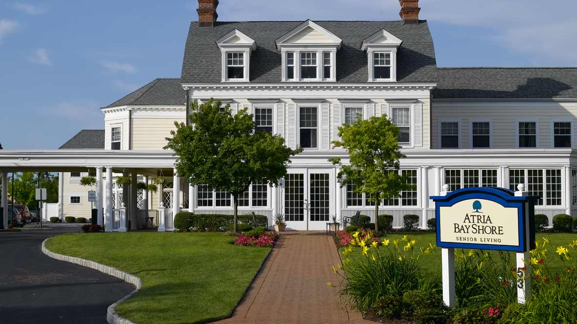 A charming two-story house with a manicured garden and brick pathway.
