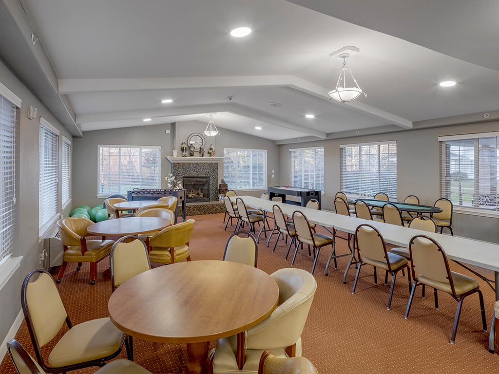 A well-lit conference room with multiple tables and chairs arranged for meetings or gatherings.