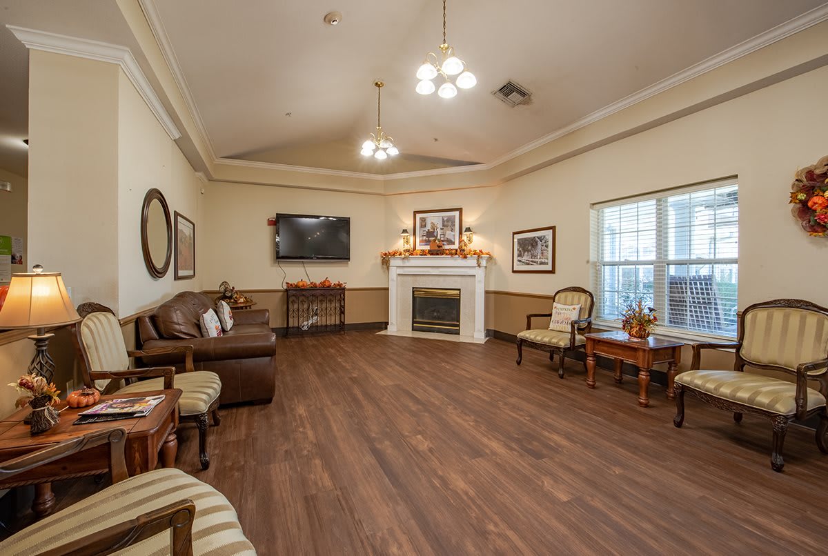 A cozy living room with a fireplace, wooden flooring, and comfortable seating.