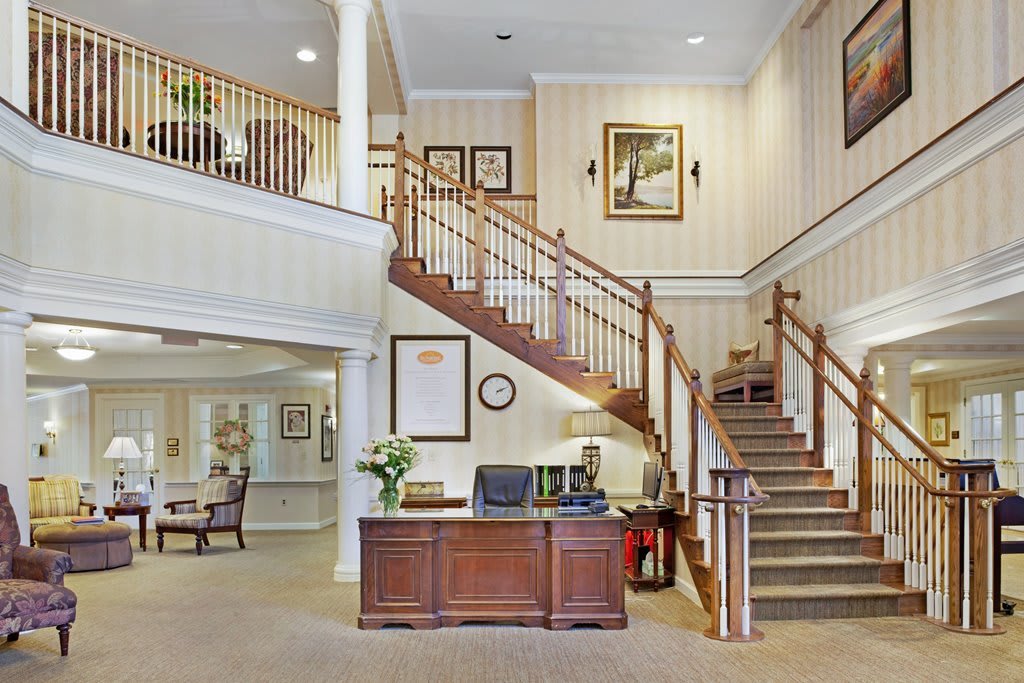 A welcoming lobby with a wooden reception desk and elegant staircase.