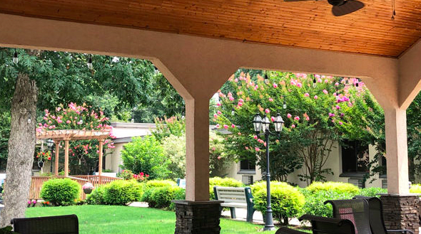 A scenic garden view from a covered patio, featuring lush greenery and a cozy bench.