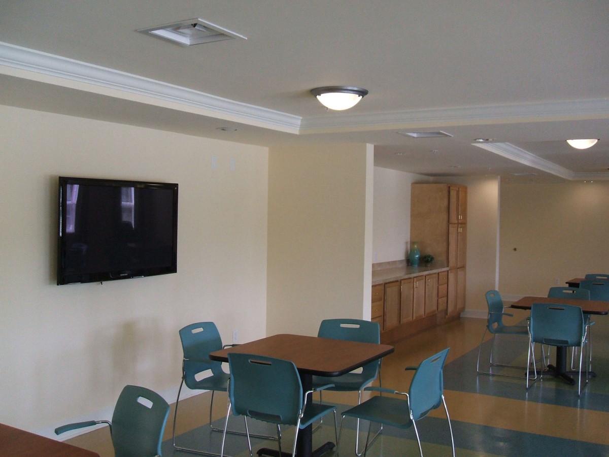 A modern cafe interior with tables, chairs, and a wall-mounted television.