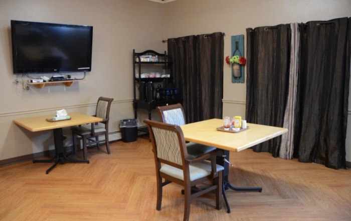 A cozy dining area with tables, chairs, a television, and decorative elements.