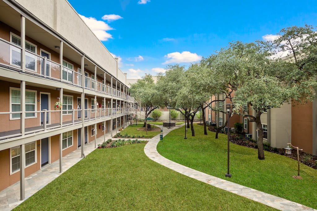 A view of an apartment building with a well-maintained courtyard and landscaped garden.