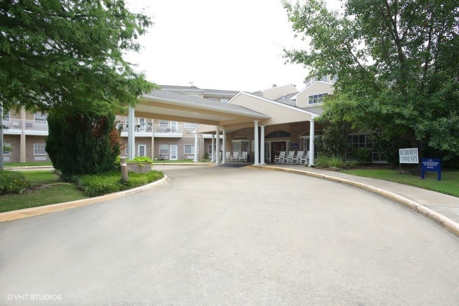 A building entrance with a covered driveway and surrounding greenery.