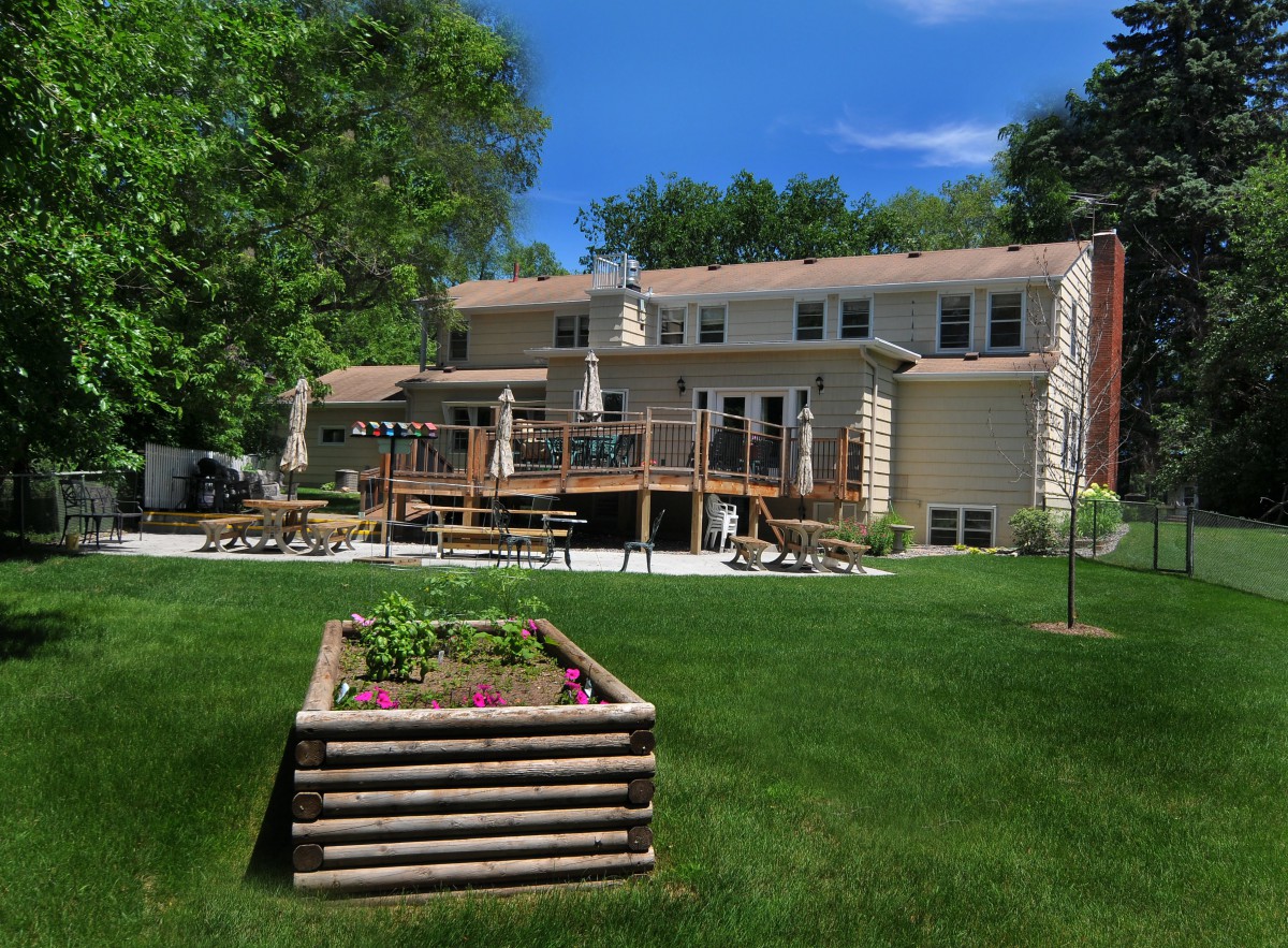 A spacious backyard featuring a large wooden deck and a garden box on a well-maintained lawn.