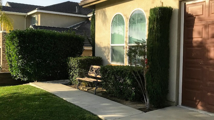 A cozy garden scene with a bench by the pathway in front of a house.
