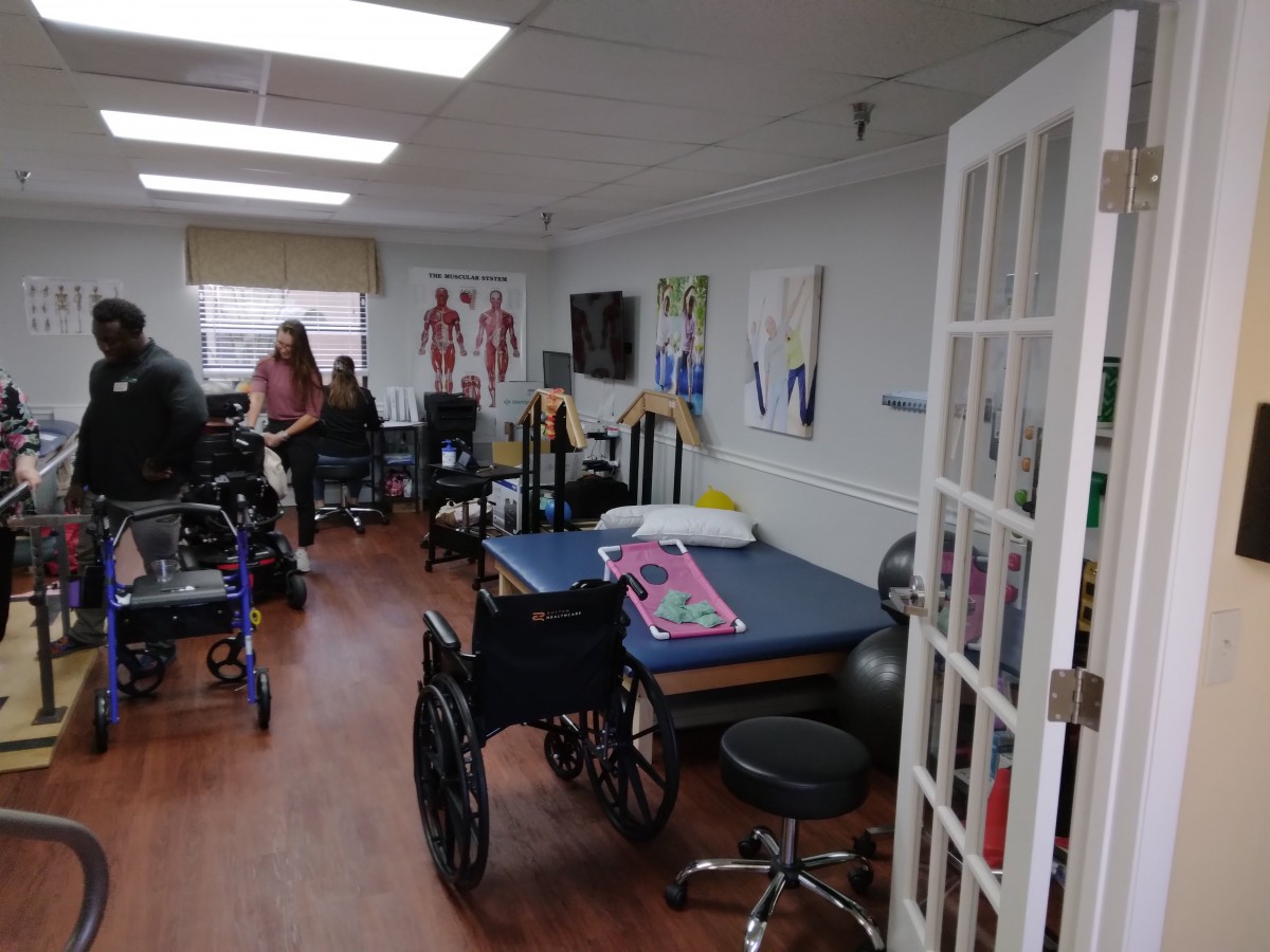 A rehabilitation room equipped with wheelchairs, therapy tables, and exercise equipment.