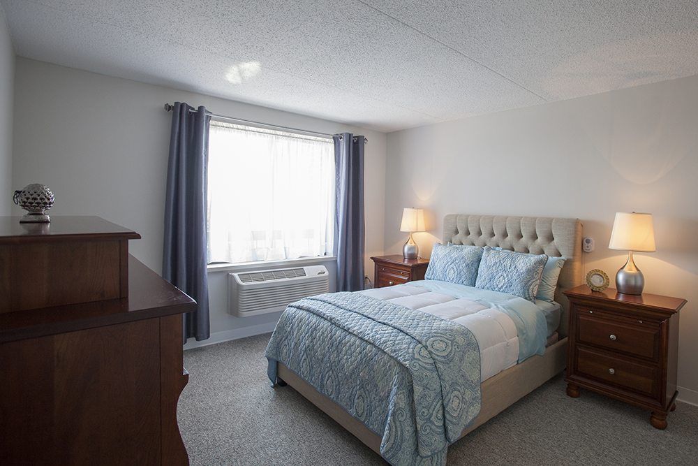 A cozy bedroom with a bed, nightstands, and a window with curtains.