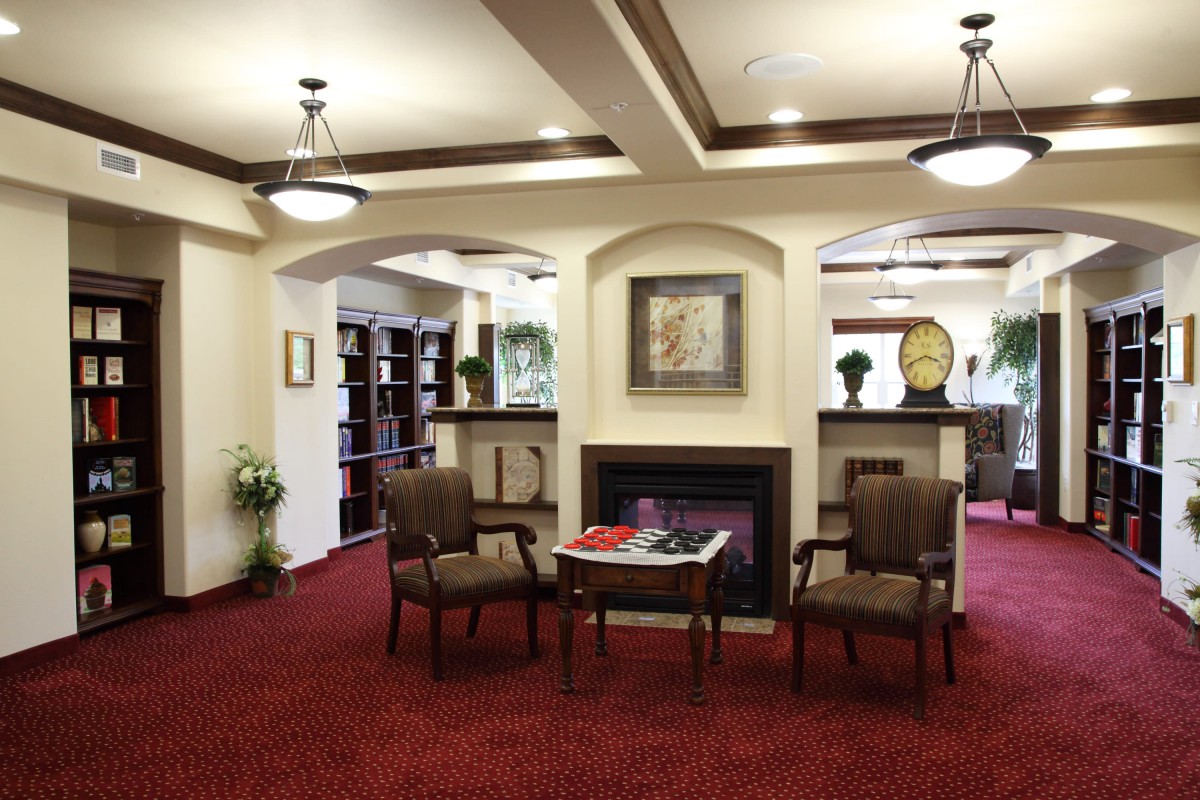 A welcoming lobby area featuring comfortable seating, a fireplace, and bookshelves.