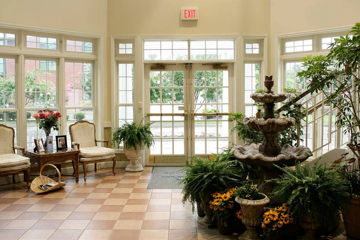 A well-lit lobby featuring a decorative fountain and lush greenery.