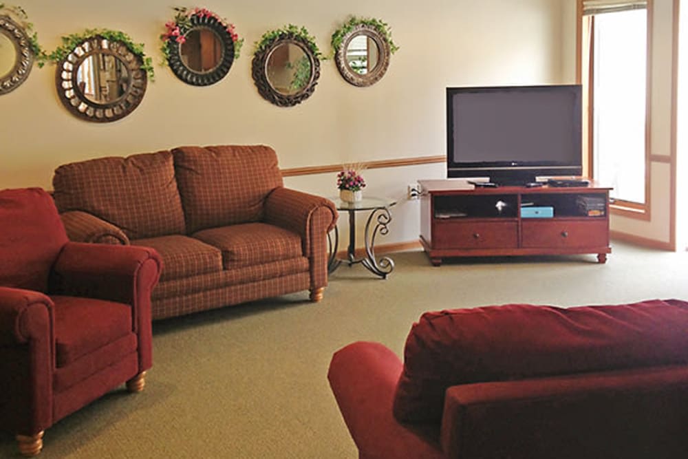 A cozy living room with comfortable seating, a TV, and decorative wall mirrors.